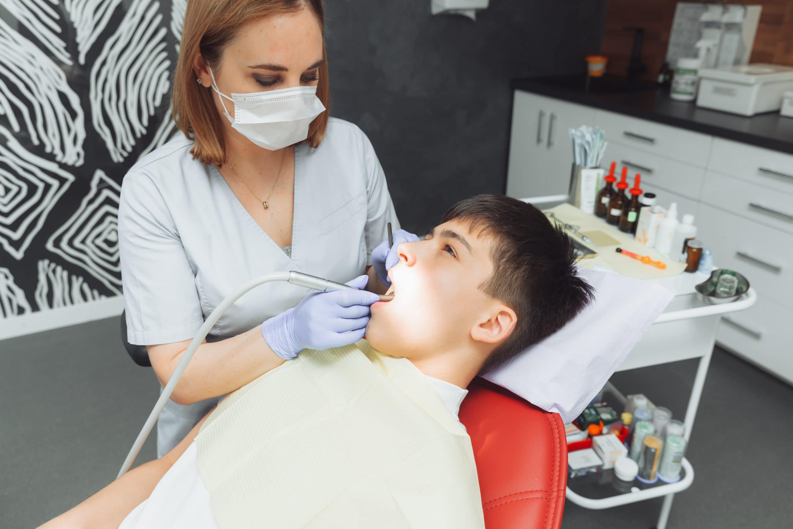 drilling teeth and sucking saliva with an ejector. dentist treats patient's teeth in modern dental office.